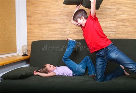 Siblings Having Pillow Fight On A Couch Confined At Home During Self