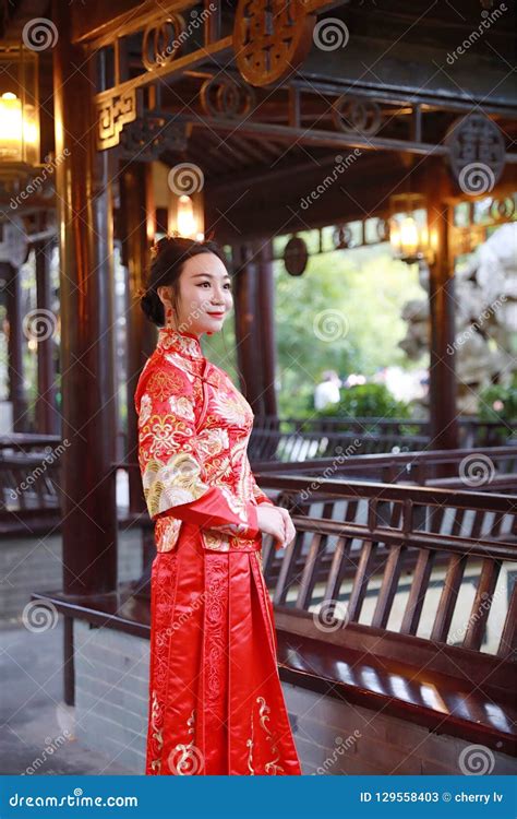 chinese woman wearing a typical chinese bride`s silk red dress adorned