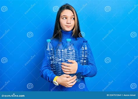 Young Brunette Girl Holding Recycling Plastic Bottles Smiling Looking