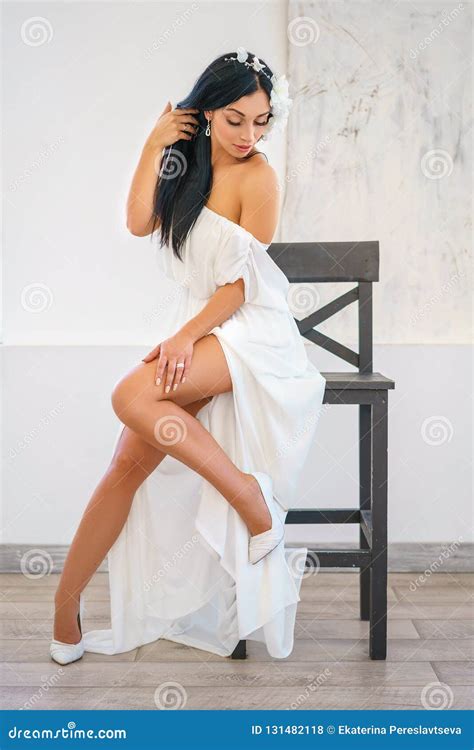 Beautiful Young Woman In White Dress Sitting Posing On Chair Stock