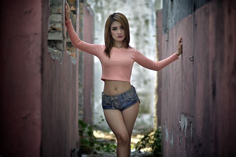 woman wearing pink long sleeved crop top and faded denim short shorts
