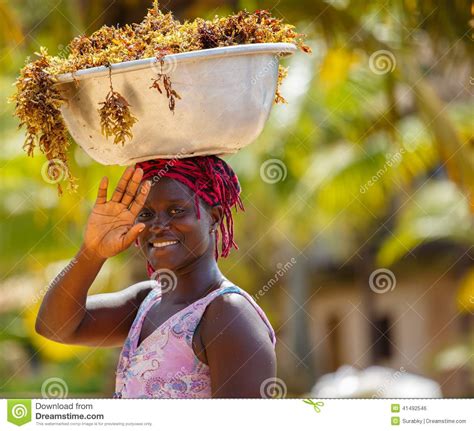 la femme africaine portent des choses sur sa tête photo éditorial