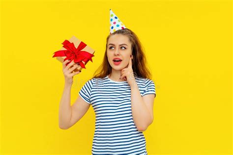 curious brunette girl in party cone on head celebrating birthday