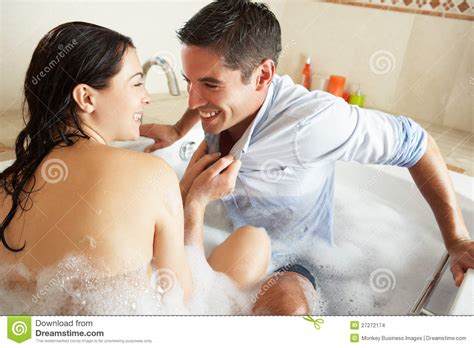 Woman Pulling Clothed Man Into Bubble Filled Bath Stock