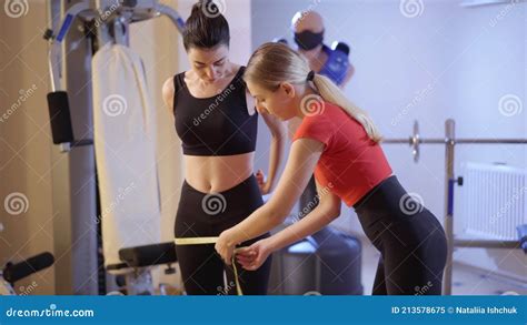 confident strict caucasian personal trainer measuring hips of