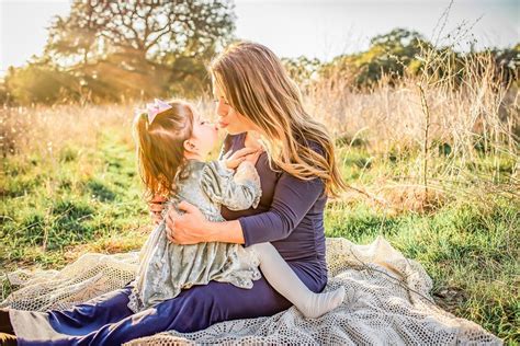 mother and daughter sharing a kiss with one another while sitting in