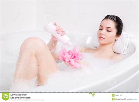 jonge vrouw in een bad met schuimspons ter beschikking