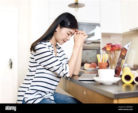 Young Asian Woman Working From Home Sitting At Kitchen Counter Thinking
