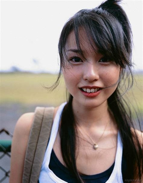 A Woman With Long Black Hair Wearing A White Tank Top And Smiling At