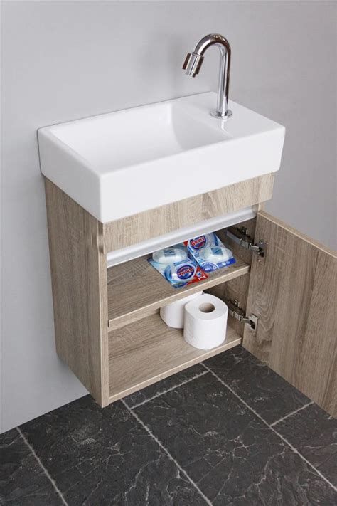 white sink sitting   bathroom mirror    toilet paper dispenser