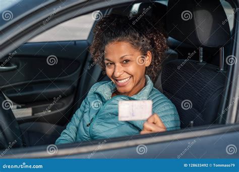 black car driver woman smiling showing  drivers license stock photo