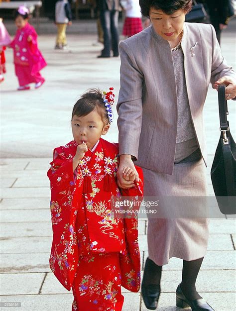 a japanese mother with her daughter sucking on a lollipop rushes to