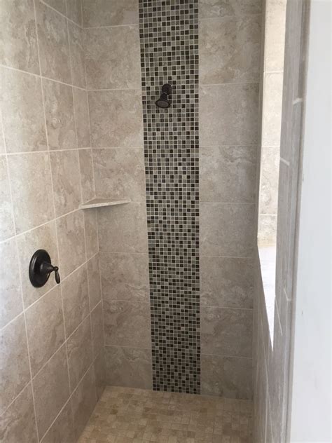 decorative mosaic tile strip done vertically in the shower lends the