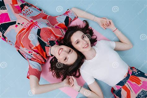 female friendship of two twin sisters holding each other`s hands stock