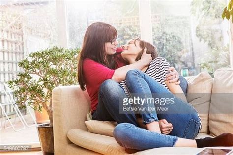 Lesbian Couple Cuddling On Sofa In Livingroom Cuddling Couples