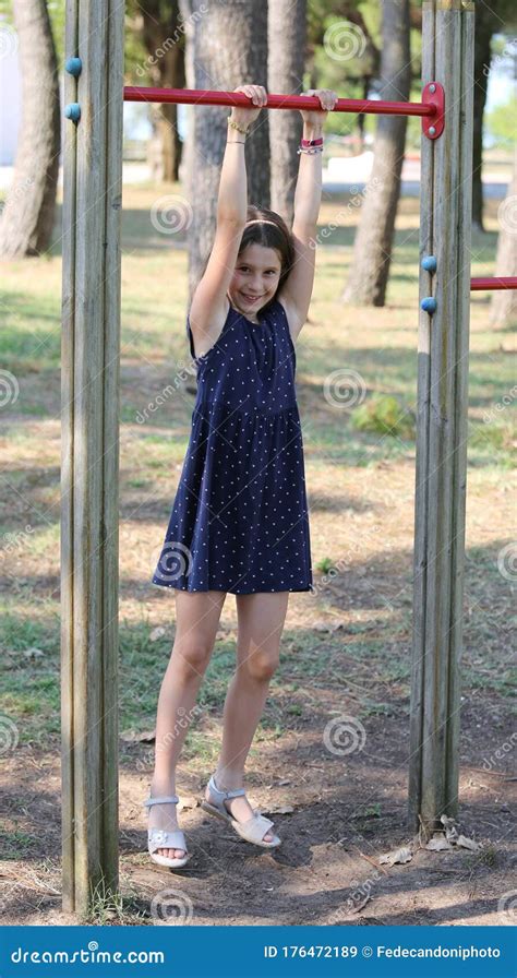 pretty girl does gymnastics on the playground with blue dress royalty