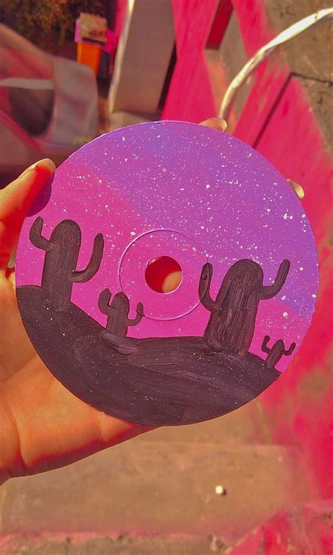 person holding   pink  purple doughnut  cactus designs