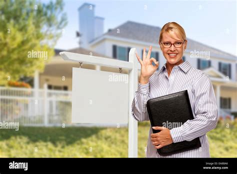 Attractive Female Real Estate Agent In Front Of Blank Real Estate Sign