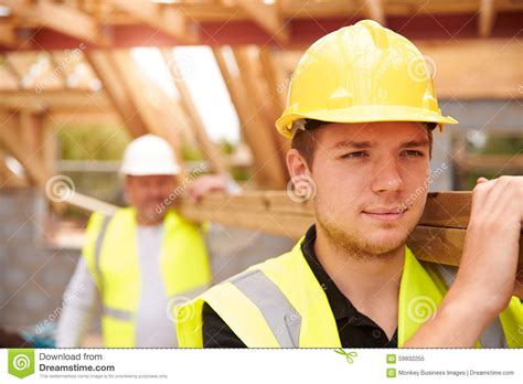 builder  apprentice carrying wood  construction site stock image