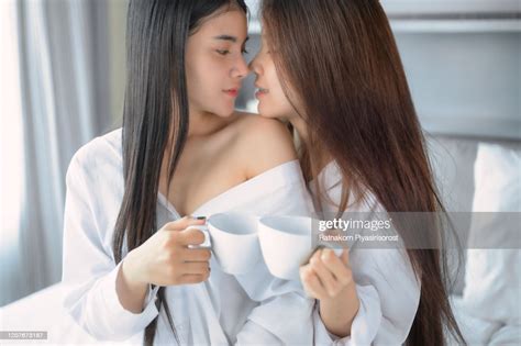 asia lesbian lgbtq couple sitting on bed hug and kiss