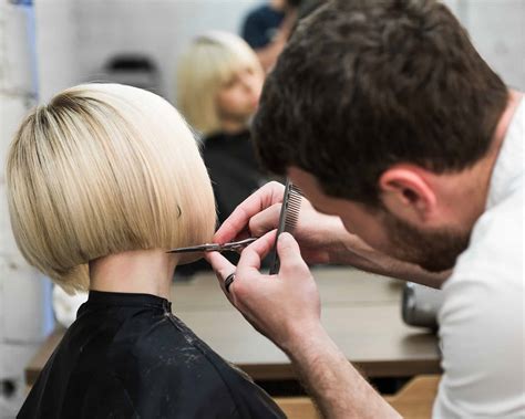 hairdresser cutting clients hair  salon  electric razor closeup