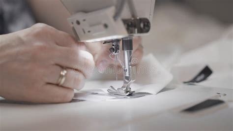 sewing white cloth   white sewing machine close  female hands