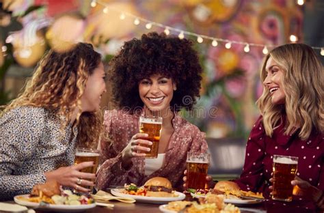 Multi Cultural Group Of Female Friends Enjoying Night Out Eating Meal