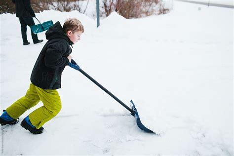 boy shoveling snow   driveway  stocksy contributor kelly knox