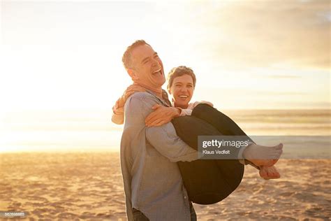 mature man carrying girlfriend on the beach photo getty images
