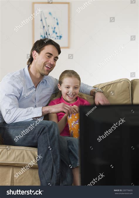 Father And Daughter Sharing Popcorn While Watching