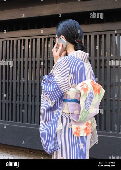 Japanese Woman In Kimono Speaking On Her Smartphone While Walking Stock