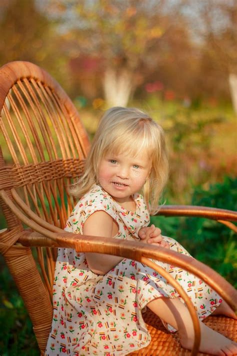 een klein meisje zit  openlucht op een stoel stock foto image  activiteit gazon