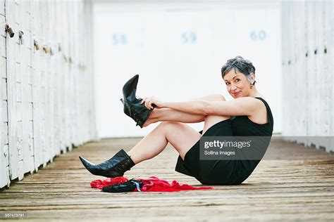 Older Caucasian Woman Taking Off Boots On Wooden Dock Photo Getty Images