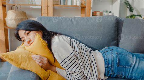 joven mujer asiática se acuesta en un cómodo sofá en la sala de estar