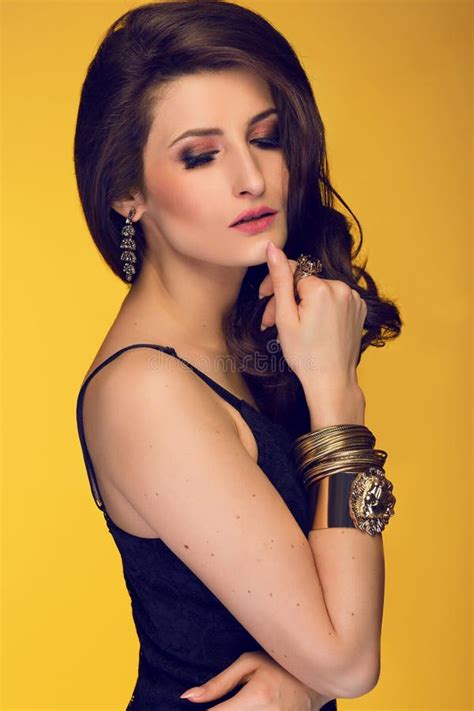 sensual beautiful brunette woman posing in black dress and gold stock