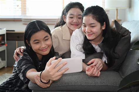 cheerful asian girls taking selfie with smart smartphone while sitting