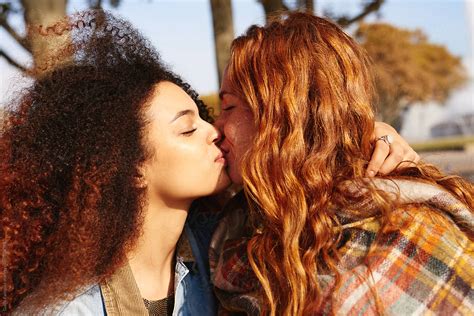 diverse lesbian couple kissing in park by guille faingold