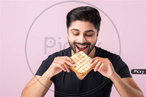 Image Of Indian Handsome Young Man Eats Bread Sandwich Showing Or