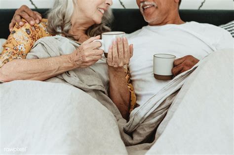 Cheerful Elderly Couple Having A Morning Coffee In Bed Premium Image