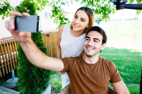 Beautiful Young Couple Taking Selfie While Sitting At Cafe`s Garden
