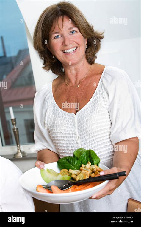 Portrait Of A Smiling Mature Woman Holding A Plate Of Food Sweden Stock