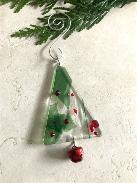 A Glass Christmas Tree Ornament Hanging From A Pine Branch With Red