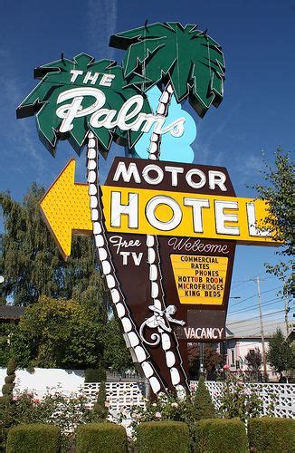 The Palm Motor Hotel Sign Is In Front Of A White Picket Fence