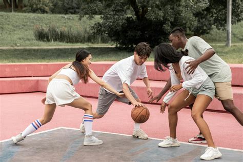 positive young diverse teenagers playing basketball  outdoor court