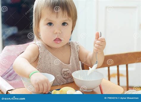 girl eating  baby sitting child eating sour cream stock photo
