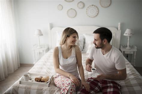 couple talking in bed and drinking coffee stock image