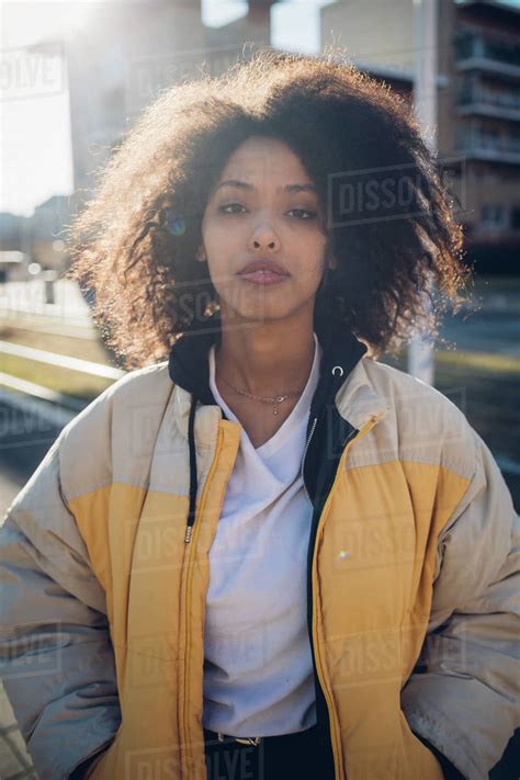 cool young woman  sunlit urban sidewalk portrait stock photo
