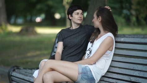deux les filles lesbiennes détente dans l parc sur un banc par