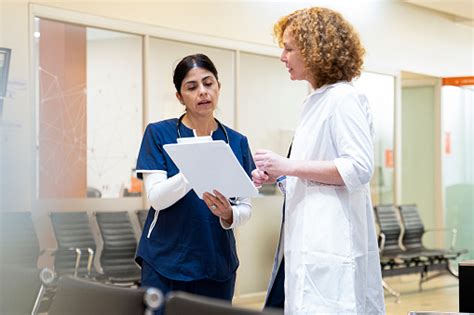 Latin American Female Nurse Discussing Over Medical Record With Doctor