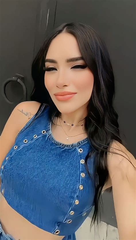 a woman with long black hair wearing a blue top